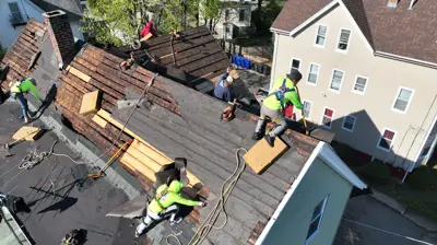 Professional roofing crew performing a full roof tear-off and deck inspection on a residential home in Rhode Island during a 2026 roof replacement project.