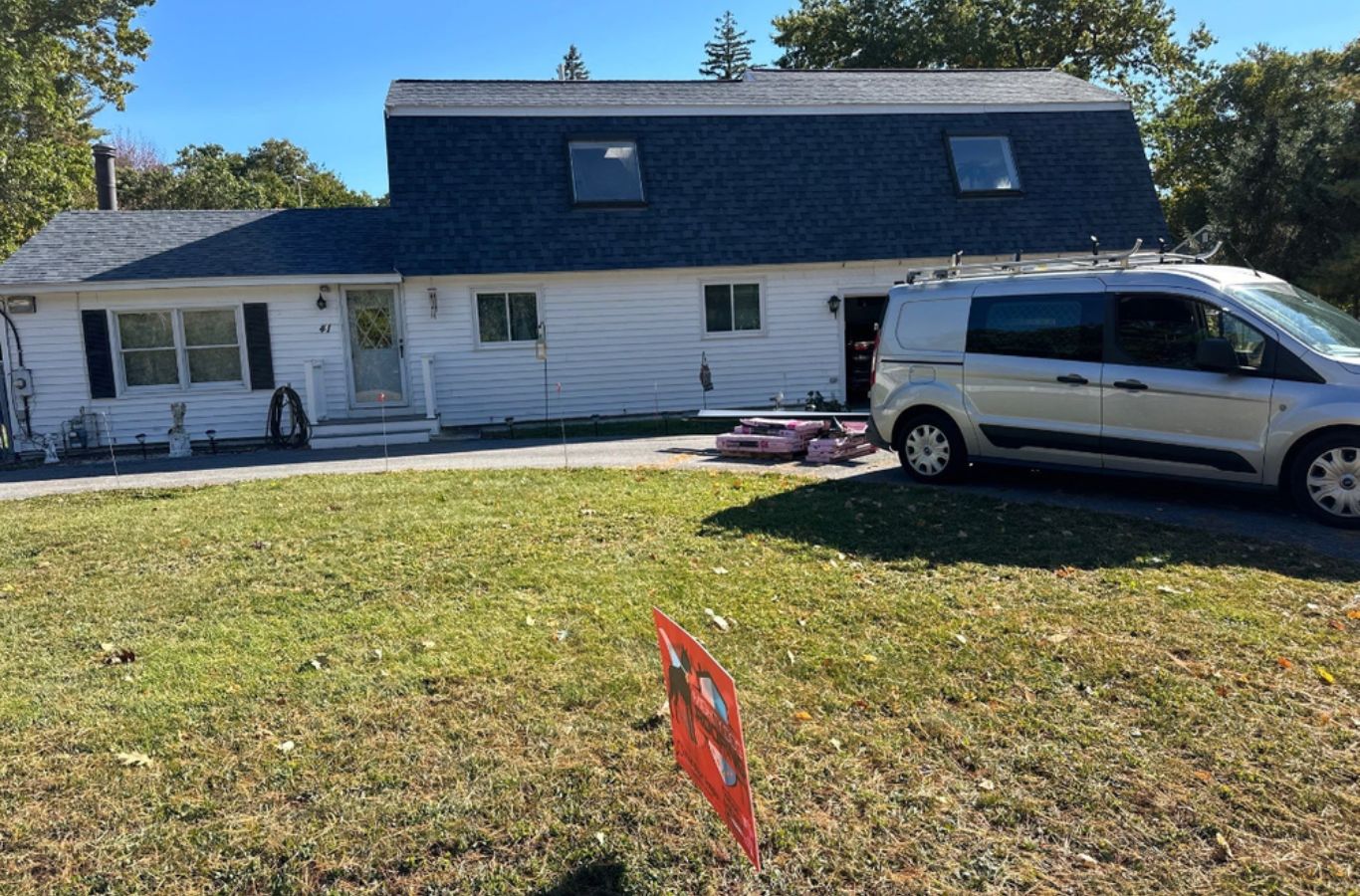 A Mighty Dog Roofing technician preparing gutters in Littleton, MA for winter-ready water flow and reduced maintenance.