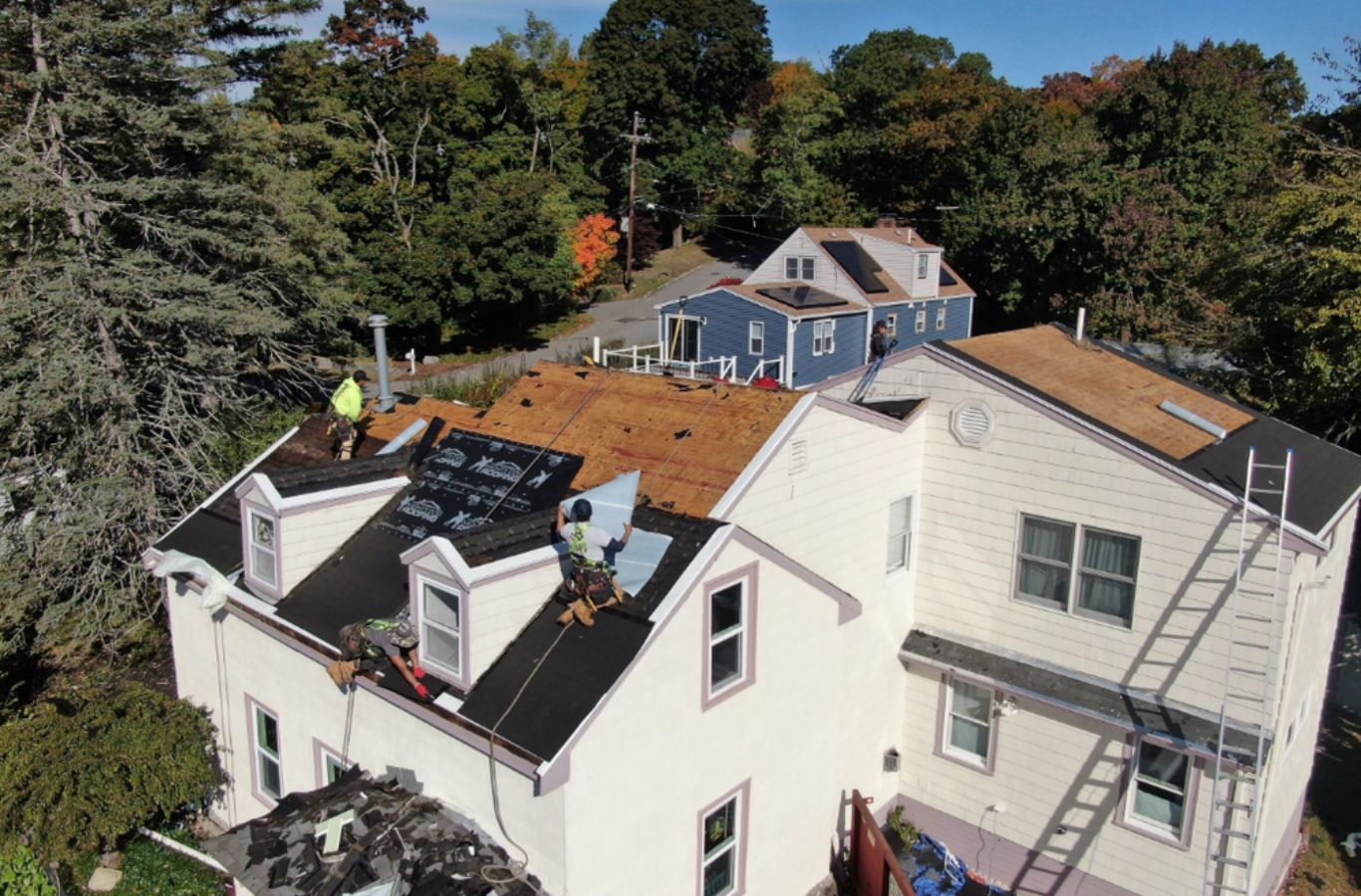 A Mighty Dog Roofing of Greater Middlesex County crew working on roof repairs in Acton, MA, highlighting quality workmanship.