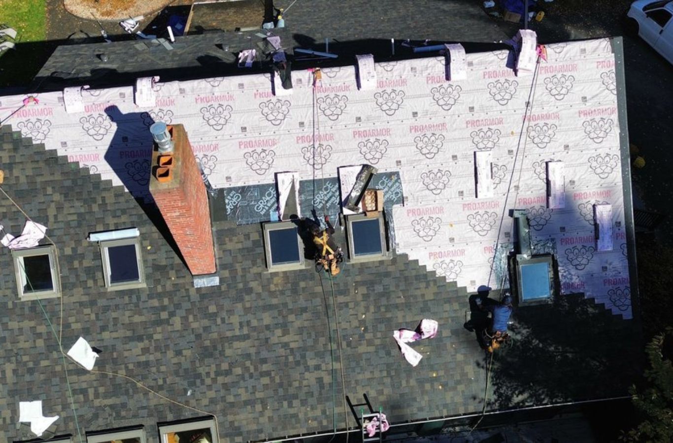 A Mighty Dog Roofing of Greater Middlesex County crew repairing a residential roof in Littleton, MA, showcasing safe and efficient methods.
