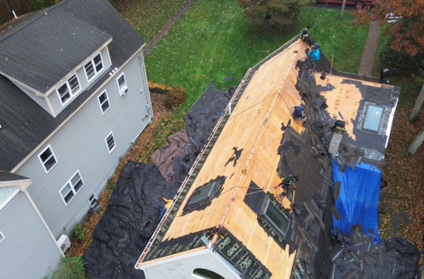 A Mighty Dog Roofing of Greater Middlesex County professional aligning roofing shingles on a home in Acton, MA, ensuring quality repair. Roof Repair near me.