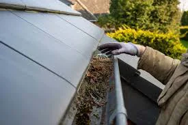 Homeowner cleaning gutters on a Thornton, CO home as part of pre-storm-season roof maintenance