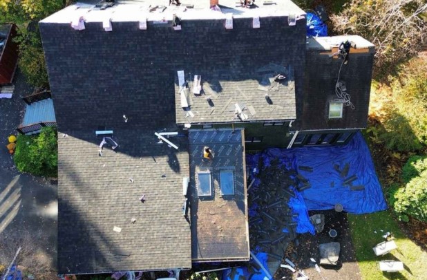 Mighty Dog Roofing contractor evaluating roof damage on a home in Dunstable, MA.