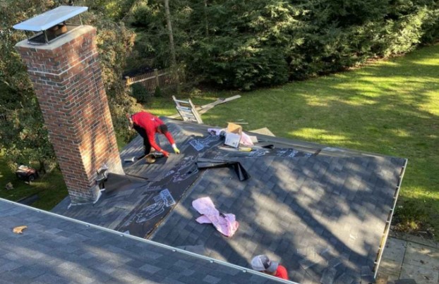 A roofing contractor evaluating a home’s roof in Wilmington, MA during a professional service visit.