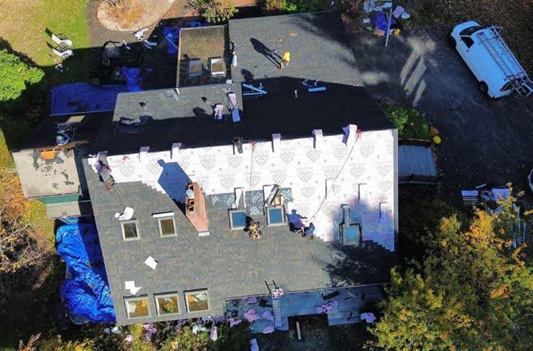 Mighty Dog Roofing crew assessing a roof on a home in Maynard, MA during a scheduled service.